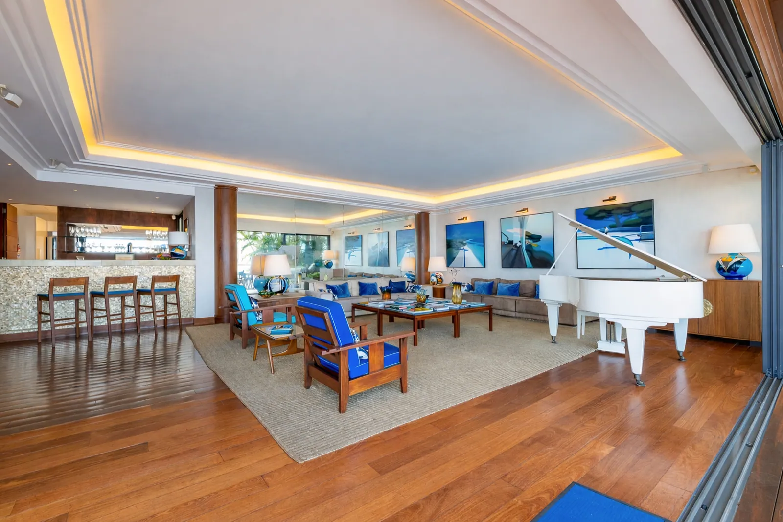 The living room and bar, grand piano beside the open terrace doors