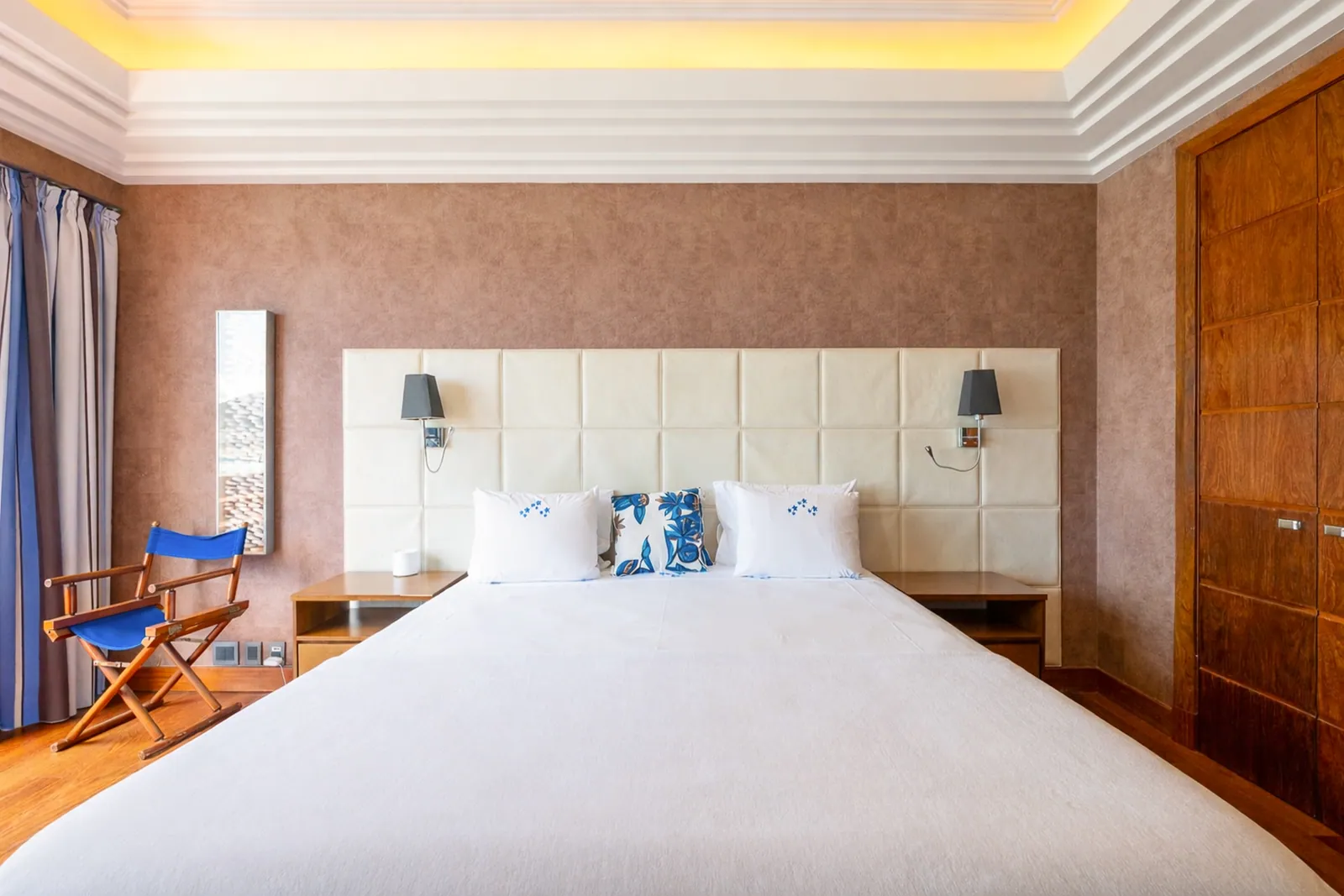 Padded headboard between two bedside lamps, wood panelling around