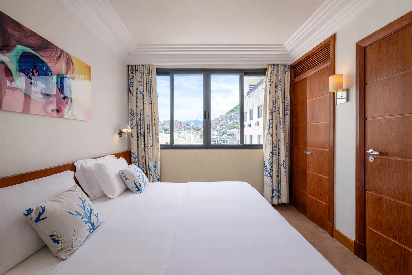 Bedroom with a wide canvas above the bed, city view through the window